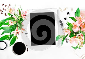 Workspace with tablet with blank screen, office accessories, coffee, flowers