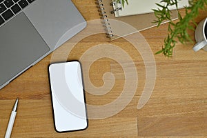 Workspace top view with smartphone mockup, laptop, pen, notepad and decor on wood tabletop