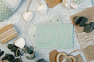 Workspace. Wedding invitation cards, craft envelopes, pink and red roses and green leaves on white background.