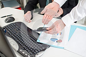 Workteam analyzing graphs and holding a calculator photo