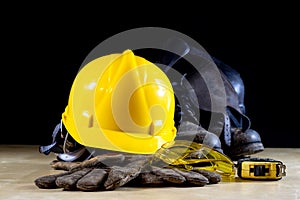 Workwear, helmet, gloves and glasses on a wooden working table.