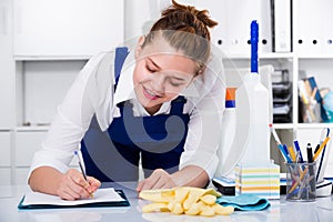 Workwoman of office cleaning service wiping dust on sleek table