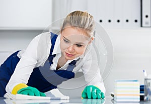 Workwoman wiping dust in office