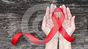 World aids day and national HIV/AIDS and ageing awareness month with red ribbon on woman hand support bow isolated