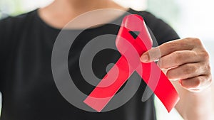 World aids day and national HIV/AIDS and aging awareness month concept with red satin ribbon on woman`s hand support