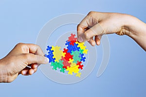 World autism awareness day concept. Children hands holding colorful puzzle heart on blue background