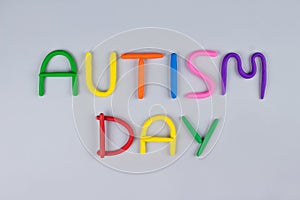World Autism Awareness Day concept - multicolored letters made of play-doh or other sensory playfoam on light gray