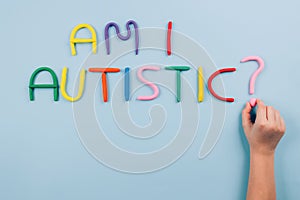 World Autism Awareness Day concept, symptoms - multicolored letters, Am I Autistic - on light blue background with child