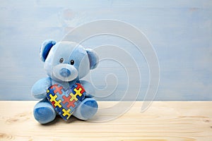 World Autism Awareness day, concept with teddy bear holding puzzle or jigsaw pattern on heart