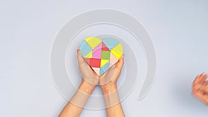 World autism awareness day concept. Woman and child hands holding puzzle heart on light blue background. Top view