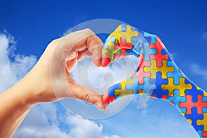 World Autism Awareness day, mental health care concept with puzzle jigsaw pattern on heart shape hands.