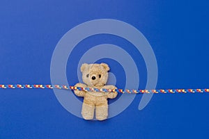 World Autism Awareness day, mental health care concept with teddy bear and ribbon puzzle pattern. On blue background
