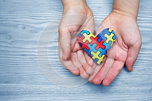 World Autism Awareness day, puzzle or jigsaw pattern on heart with autistic child`s hands