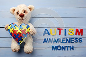 World Autism Awareness month, mental health care concept with teddy bear holding puzzle or jigsaw pattern on heart