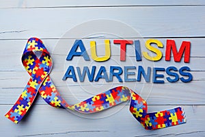 World Autism awareness and pride day or month with Puzzle pattern ribbon on blue wooden background.