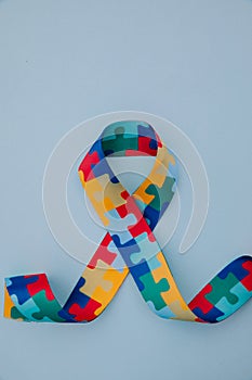 World Autism awareness and pride day with Puzzle pattern ribbon on blue background. Vertical image