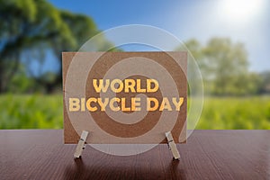 World bicycle day text on card on the table with sunny green park background