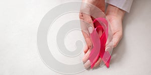 World breast cancer day. Pink ribbon with woman hands on white background. Breast cancer awareness symbol