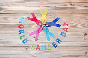 World cancer day February 4. colorful awareness ribbons; blue, red, pink and yellow color on wooden background for supporting