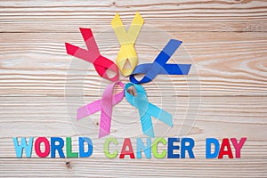 World cancer day February 4. colorful awareness ribbons; blue, red, pink and yellow color on wooden background for supporting