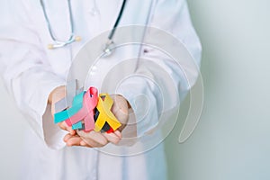 World cancer day, February 4. Doctor hold colorful ribbons, blue, yellow, red, green, white, pink and grey for supporting people