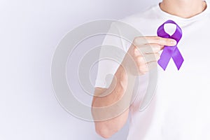 World cancer day, hands holding purple ribbon on grey background with copy space for text. Healthcare and medical concept