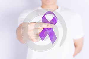 World cancer day  hands holding purple ribbon on grey background. Healthcare and medical concept