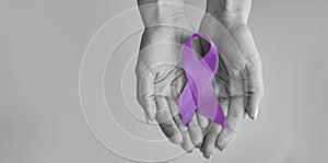 World cancer day inscription. healthcare and medicine concept - girl hands holding Purple cancer awareness ribbon.