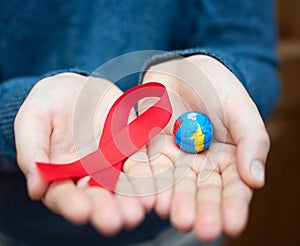 World day of fight against AIDS. The symbols are a red ribbon and an imitation of a globe in the hands of a person. This