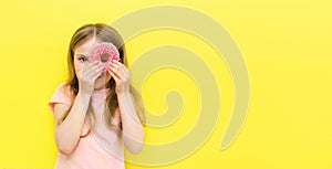 World Donut Day or No diet day. A little girl holding donuts and smiling, holding on a yellow background. The concept. kids and