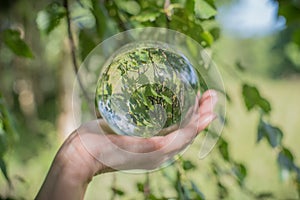 World environmental concept. Crystal globe in human hand on beautiful green and blue bokeh