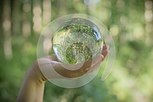 World environmental concept. Crystal globe in human hand on beautiful green and blue bokeh