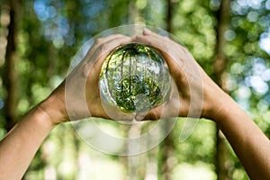 World environmental concept. Crystal globe in human hand on beautiful green and blue bokeh