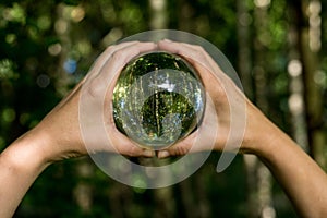 World environmental concept. Crystal globe in human hand on beautiful green and blue bokeh