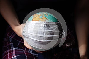 World Epidemic Danger, earth globe with a face mask for protection. Black background