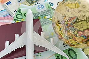 World and Europe travel concept as toy airplane on passport, globe on pile of euro banknotes