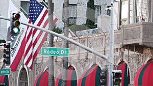 World famous Rodeo Drive Street Road Sign in Beverly Hills against American Unated States flag. Los Angeles, California, USA. Rich