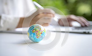 World globe with businesswoman and computer laptop at the background