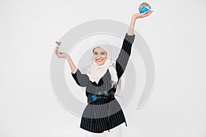 A world of harmony, save earth, time concept. Pretty Muslim girl in white hijab holding earth globe in one hand, and an