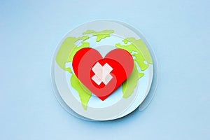 World health day concept. Paper model of earth globe, heart with cross on blue background