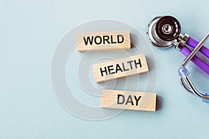 World Health Day, medical and healthcare. Stethoscope and text World Health Day in wooden cubes on blue background