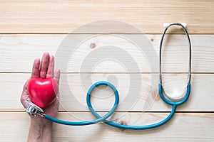 World heart health day concept with red heart and medical doctor stethoscope on aged woman hand for medical wellness