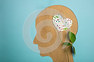 World Heart and Mental Health Day. Paper Cut as Human Head with Leaf Tree and Colorful Heart Shape Flower inside the Brain photo