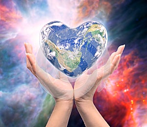 World in heart shape with over women human hands.