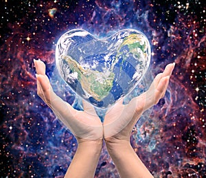 World in heart shape with over women human hands
