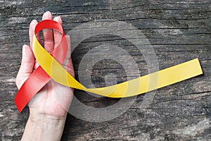 World hepatitis day and HIV/ HCV co-infection awareness with red yellow ribbon  isolated  with clipping path on person`s hand