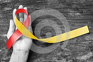 World hepatitis day and HIV/ HCV co-infection awareness with red yellow ribbon isolated  with clipping path on person`s hand