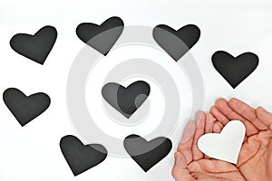 World humanitarian day, kindness, pure heart and spread love concept. Hand holding white heart among black ones.