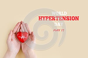 World Hypertension Day. Women& x27;s hands hold red heart with heartbeat chart - a symbol of high blood pressure