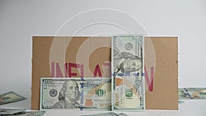 World inflation concept. Cardboard with word inflation and falling usd banknotes